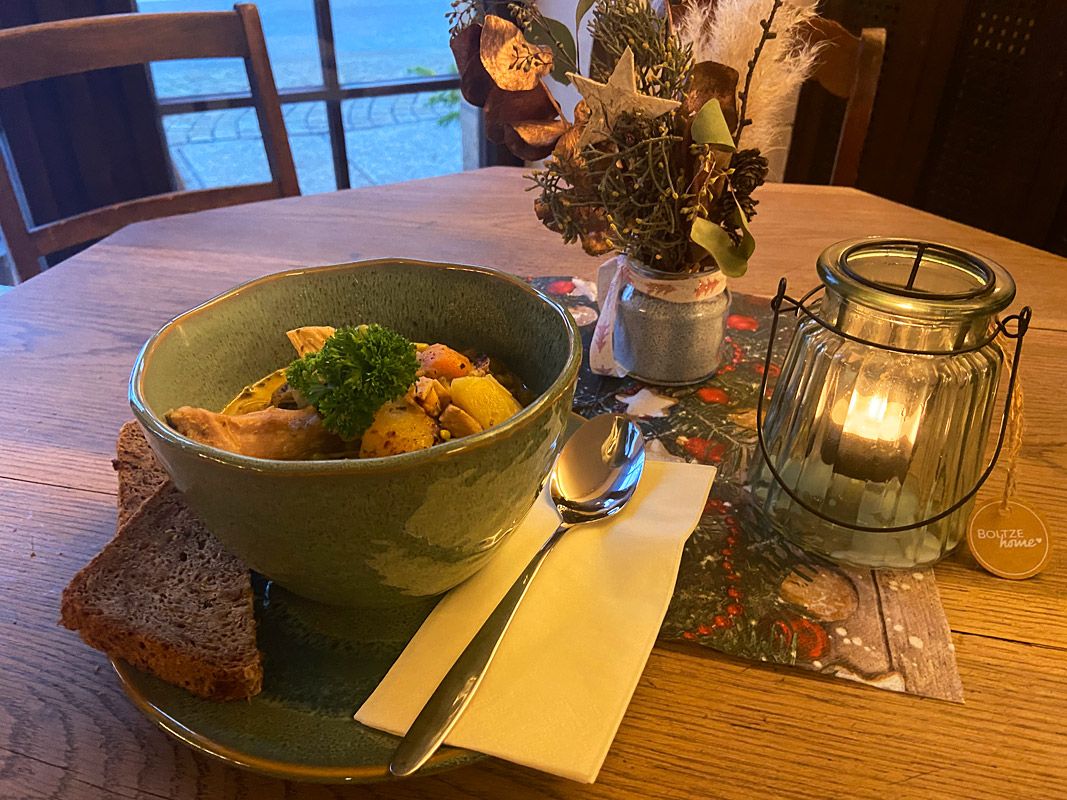 Kerze, Blumen und eine Schale Salat auf einem Holztisch